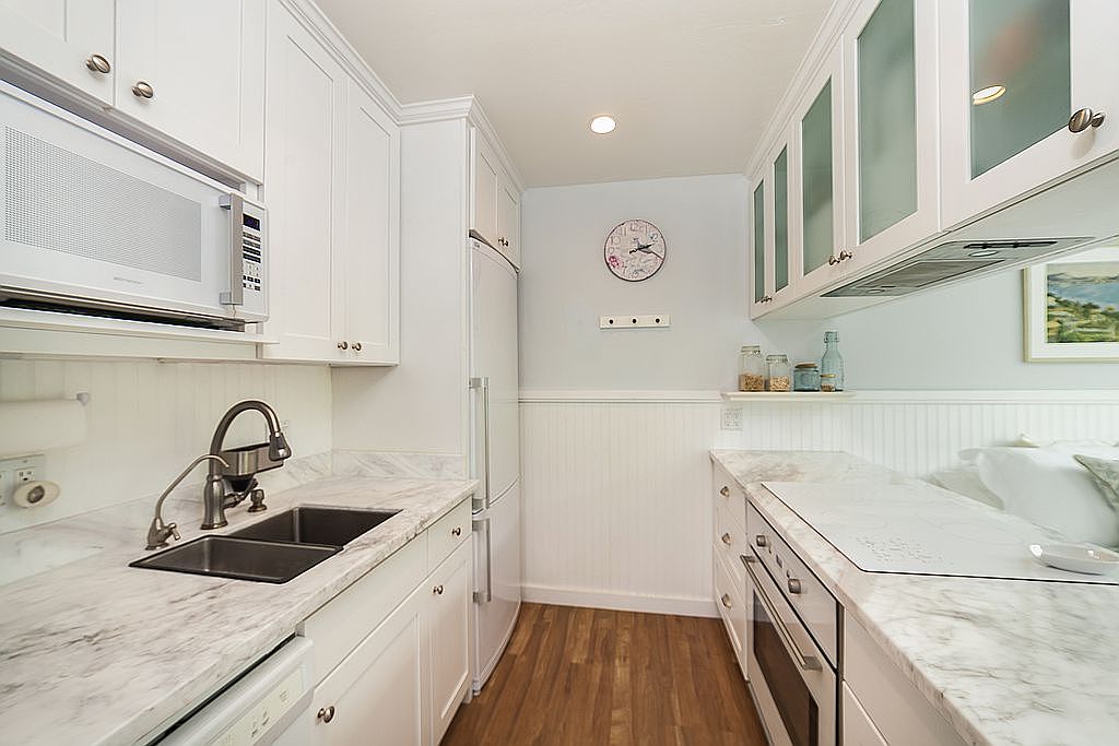Kitchen with marble counters and white cabinetry