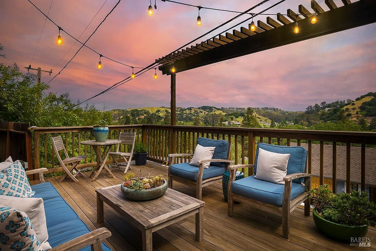 The redwood deck at 40-42 Arenal Avenue at twilight, string lights overhead, Mt. Tam ridgeline beyond